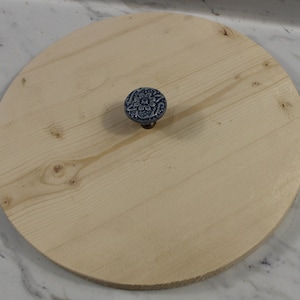 May include: A round wooden lid with a blue and white floral knob.