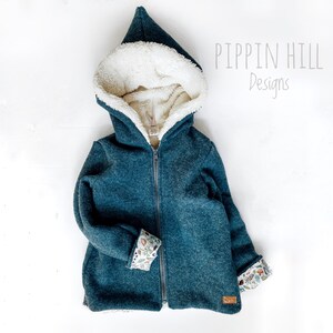May include: A teal blue hooded jacket with a white sherpa lining. The jacket has a zipper closure and features a floral print on the cuffs. The text "Pippin Hill Designs" is visible in the top right corner of the image.