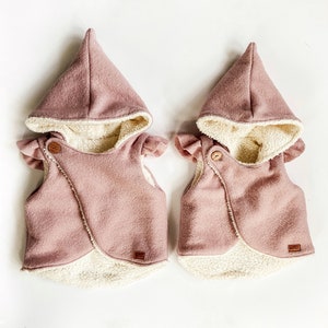 Puede incluir: Dos chalecos de forro polar rosa con forro de sherpa blanco y mangas con volantes. Los chalecos tienen un frente cruzado y un cierre de botón.