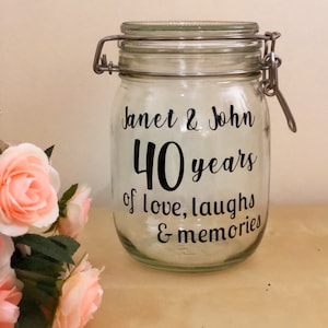 Könnte beinhalten: Ein klares Glasgefäß mit einem Metalldeckel und einem schwarzen Vinyl-Aufkleber mit der Aufschrift "Janet & John 40 Jahre voller Liebe, Lachen und Erinnerungen".