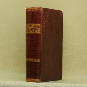 May include: A vintage, red leather-bound book titled "The Modern Cyclopedia" with gold lettering and decorative patterns on the spine.