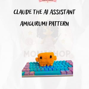 May include: A crochet amigurumi pattern featuring a small orange rectangular character with black square eyes, sitting on a computer keyboard with purple and blue keys. The text reads CLAUDE THE AI ASSISTANT AMIGURUMI PATTERN and MOMISHOP.