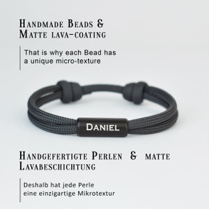 Pu&ograve; includere: Un braccialetto intrecciato grigio con un'etichetta in metallo nero che dice "DANIEL". Il braccialetto &egrave; realizzato con perline fatte a mano e ha un rivestimento in lava opaca.