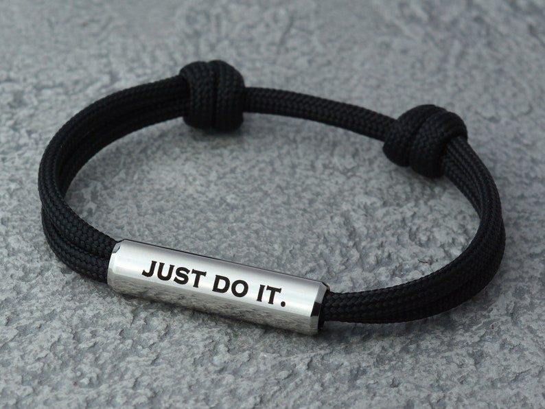 May include: Black braided bracelet with a silver bar that reads "JUST DO IT."