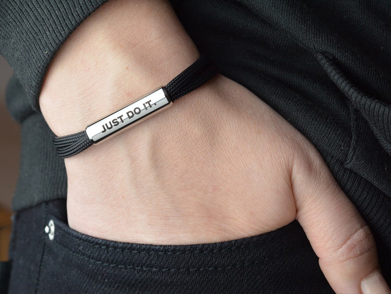 May include: A black adjustable bracelet with a silver bar that reads "JUST DO IT."
