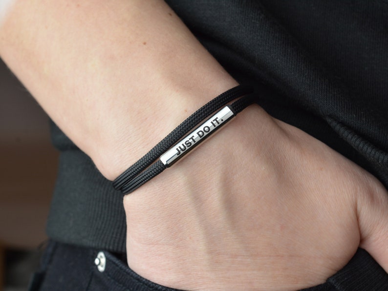 May include: Black bracelet with a silver bar that reads "JUST DO IT."