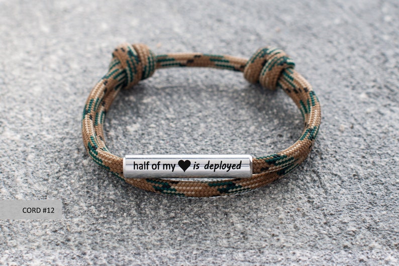 May include: A brown and green camouflage paracord bracelet with a silver metal charm that reads "half of my heart is deployed".
