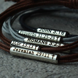 Puede incluir: Cinco pulseras de cuero con dijes de metal plateado. Cada dije tiene un versículo bíblico diferente grabado. Los versículos son: Juan 3:16, Proverbios 31:25-29, Romanos 3:23, 1 Corintios 13:13 y Jeremías 29:11.