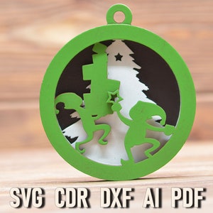 May include: Green Christmas ornament with a white and black design of two elves holding a star and a Christmas tree. The ornament is laser cut and ready to be assembled.