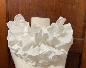May include: A white ruffled collar made of fabric. The collar is layered and has a soft, delicate look.