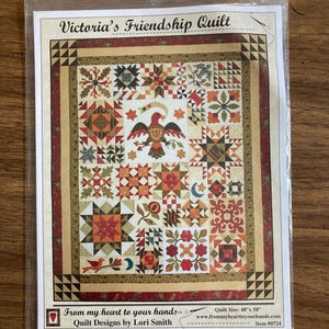May include: A packaged quilt pattern titled "Victoria's Friendship Quilt." The quilt design features a central eagle motif, surrounded by various star and floral patterns in shades of red, orange, and brown. The quilt size is 48" x 58".