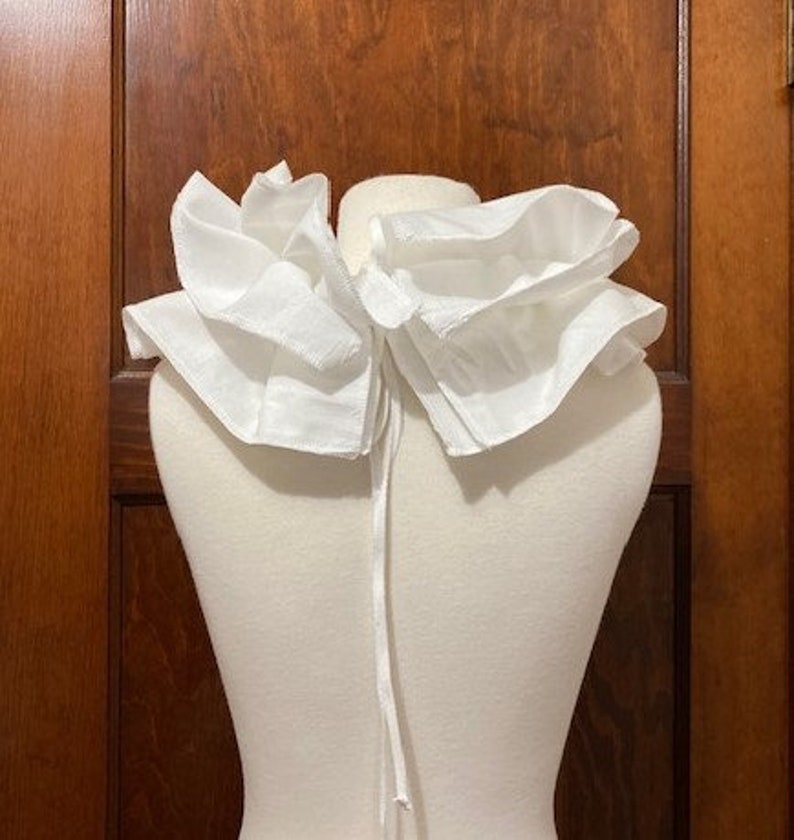 Peut inclure: Un col en dentelle blanc avec une fermeture &agrave; nouer. Le col est fait d'un tissu doux et l&eacute;ger, parfait pour ajouter une touche d'&eacute;l&eacute;gance &agrave; n'importe quelle tenue.