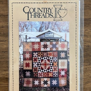 May include: A package for a quilt pattern titled "Piecing Is Fine #641" by Country Threads. The pattern features a colorful star quilt design with various fabric squares in shades of brown, red, and green. The package is sealed in a clear plastic bag.