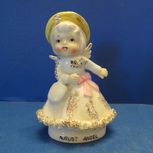 Norcrest August Angel indossa un cappello giallo, tiene in mano una borsa blu, indossa un abito bianco e oro con una fascia rosa, in meravigliose condizioni vintage!