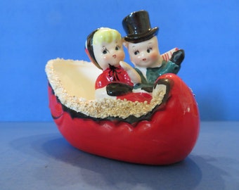 Ucagco Boy & Girl in Sleigh - Scraf is Flying in the Breeze! She Wears Red Dress w Hat - He Wears Tophat w Green Coat - Excellent!