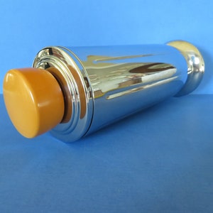 以下が含まれることがあります： 明るいオレンジ色のプラスチック製のトップが付いたシルバーの칵테일シェーカー。シェーカーは溝のあるデザインで、丸みを帯びた底になっています。