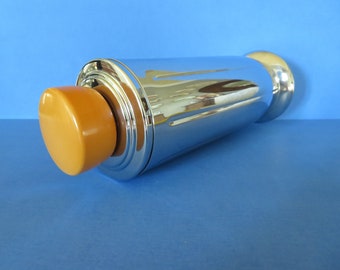 Puede incluir: Un coctelera de plata con una tapa de plástico naranja brillante. La coctelera tiene un diseño acanalado y un fondo redondeado.