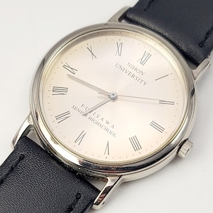 Könnte beinhalten: Eine silberne Armbanduhr mit schwarzem Lederarmband. Das cremefarbene Zifferblatt hat römische Ziffern und den Text "NIHON UNIVERSITY FUJISAWA SENIOR HIGHSCHOOL". Die Uhr hat ein klassisches Design.