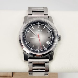 May include: A silver wristwatch with a textured grey face and a red second hand. The watch features the text "TAKEO KIKUCHI" and a date display. The watch is on a silver metal strap.