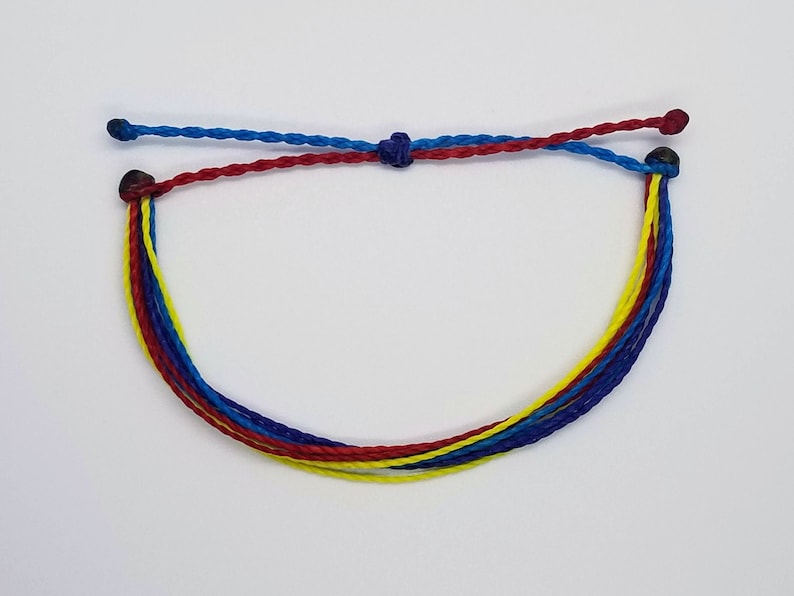 May include: A multi-strand bracelet with blue, red, and yellow cords tied together with a knot. The ends of the cords are secured with dark brown beads.