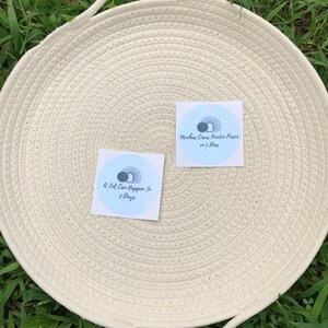 May include: Two white square stickers with blue and gray circular designs. The text on the stickers reads "A lot can happen in 3 days" and "Muchas Cosas Pueden Pasar en 3 Dias".