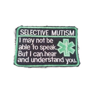 May include: Black and green embroidered patch with the text "SELECTIVE MUTISM I may not be able to speak. But I can hear and understand you." and a green medical symbol.