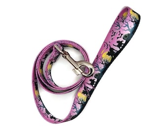 May include: A pink dog leash with a black and white Halloween-themed print. The leash has a silver metal clip.