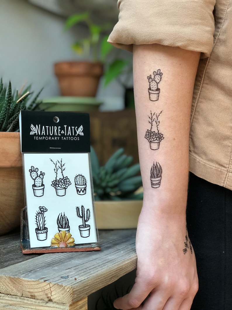 May include: A sheet of temporary tattoos featuring six different potted cactus and succulent designs. The sheet is labeled "Nature Tats Temporary Tattoos".