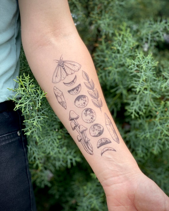 Hand poked moon phases tattoo on the inner forearm.