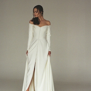 Modern off-shoulder wedding dress with a slit Off-the-shoulder long sleeve crepe bridal gown Minimalist button front wedding gown  SERENA