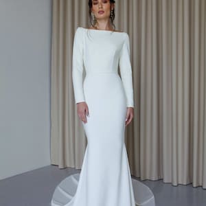 May include: A white, long-sleeved wedding dress with a fitted bodice and a flowing skirt.