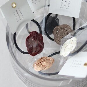 Puede incluir: Primer plano de cuatro gomas para el pelo con nudos de diferentes colores. Las gomas para el pelo est&aacute;n en un recipiente transparente con etiquetas blancas que tienen texto japon&eacute;s.