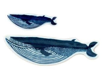 May include: Two blue and white ceramic whale-shaped serving platters. The larger platter is 17 inches long and the smaller platter is 10 inches long.