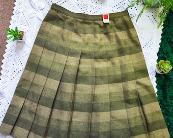 May include: A pleated skirt in shades of olive green and tan, featuring a striped pattern. The skirt has a classic A-line silhouette and a visible tag. The garment is displayed on a white crocheted surface.