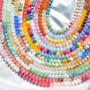May include: A collection of beaded necklaces in various colors, including pink, red, orange, yellow, green, blue, and white. The beads are small and round, and the necklaces are arranged in a circular pattern.