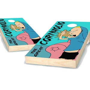 May include: Two wooden cornhole boards with a cartoon graphic of a character eating food. The boards have a light blue background with the words "CORNHOLIO" and "THE GREAT" printed on them. The character is wearing a blue shirt and black shorts.