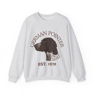 Op de afbeelding: Een lichtgrijs sweatshirt met een afbeelding van de kop van een Duitse Staande Hond in profiel. De tekst "GERMAN POINTER" staat in een boog boven de hond, met "EST. 1870" eronder. De hondengrafiek is bruin en wit.