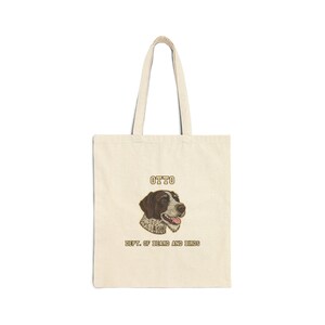 Könnte beinhalten: Cremefarbene Tragetasche mit einer Hundeillustration. Auf der Tasche steht der Name "OTTO" über dem Hunde-Bild und "DEPT. OF BEARD AND BIRDS" darunter. Der Hund hat braune und weiße Markierungen und einen fröhlichen Gesichtsausdruck.