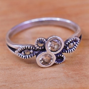 May include: A set of three ceramic mugs with a speckled, matte finish. The mugs are in shades of cream, light gray, and dark gray. Each mug has a simple, minimalist design and a rounded handle. The mugs are stacked on top of each other.