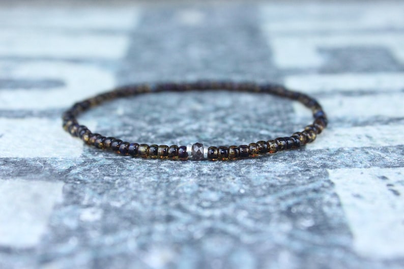 May include: A brown beaded bracelet with a single silver bead in the center.