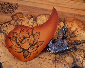 Golpeador de guitarra acústica de cuero marrón con diseño de lágrima y flor de loto tatuada.