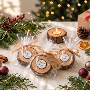 May include: Three round wood slice candles wrapped in clear plastic with beige ribbons. Labels read "Fraser Fir," "Apples & Cinnamon," and "Cosy Vanilla." A fourth wood slice candle is lit nearby. The candles feature natural bark edges and light-colored wood grain surfaces.