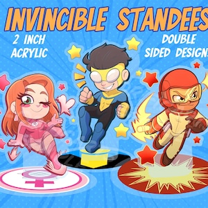 May include: Three 2-inch acrylic standees featuring Invincible characters. The left figure has orange hair and a pink suit, the center figure wears a blue and yellow suit, and the right figure wears a red and tan suit. Text reads INVINCIBLE STANDEES.