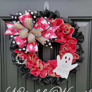 May include: A black and pink Halloween wreath with a burlap bow and a white ghost cutout that says "Happy Halloween".