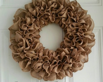 May include: A brown burlap wreath with a ruffled texture. The wreath is made of burlap fabric and is a popular choice for rustic home decor.