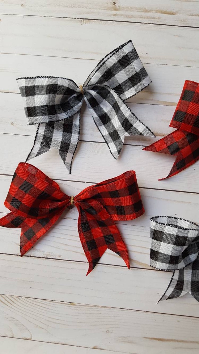 May include: Several decorative bows in a rustic style. Two bows are black and white checkered, and two are red and black checkered. The bows are tied with twine and are arranged on a light wood-grain surface.