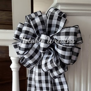 May include: A large black and white checkered bow with a black satin edge. The bow is tied on a white banister.