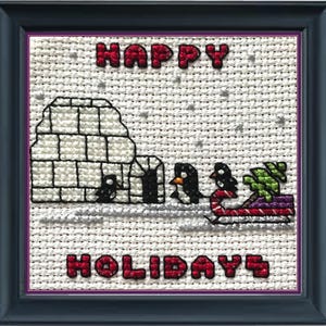 Könnte beinhalten: Kreuzstich-Design mit einem weißen Iglu mit Pinguinen und einem roten und weißen Zuckerstangen-Schlitten. Der Text "HAPPY HOLIDAYS" ist in Rot gestickt.