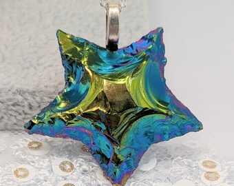 May include: A dichroic glass star pendant on a silver chain. The star pendant has a multi-colored iridescent finish with hues of blue, green, and gold. The pendant is approximately 2 inches in width and length, and is a unique piece of jewelry.