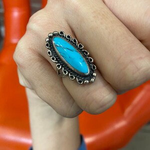 Puede incluir: Un anillo de plata con una piedra ovalada turquesa engastada en un marco decorativo de plata.